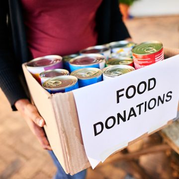 ss3 Close-up of a young woman standing outside with a box of food donations for a charitable cause